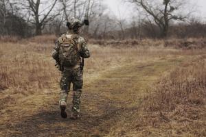 Person in military clothing walking down a dirt path